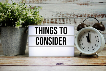 Things to Consider text on light box with alarm clock on wooden background