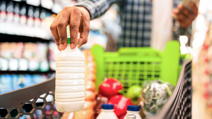 Unrecognizable Black Guy Doing Grocery Shopping Putting Products In Cart Full Of Food In...