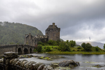 Fototapeta premium Eilean Donan Castle, a historic stone fortress in the Scottish Highlands, stands on a small island connected to the mainland by an arched stone bridge.