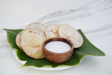 Serabi cake, a typical Indonesian cake made from rice flour, is served on a plate in a banana leaf....