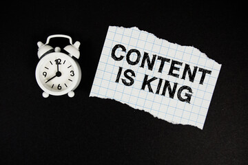 Think Big Do Bigger text written on paper with alarm clock on black background