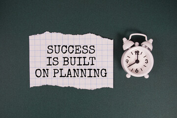 Success is Built on Planning text written on paper with alarm clock on green background