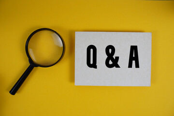 Q and A text written on paper with magnifying glass on yellow background