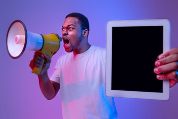 Emotional Black Guy Holding Digital Tablet With Blank Screen And Shouting To Loudspeaker, Making...