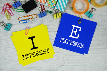 IE - Interest Expense text on stick note with stationery on concrete background