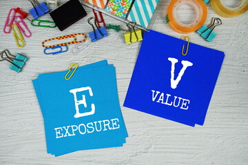 EV - Exposure Value text on stick note with stationery on concrete background