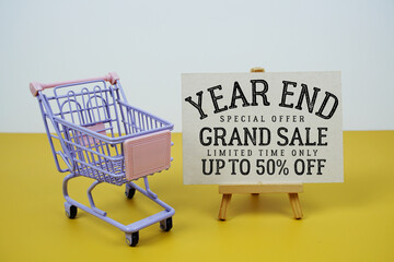 Year End Grand Sale 50% off text with mini trolley shopping cart on green background