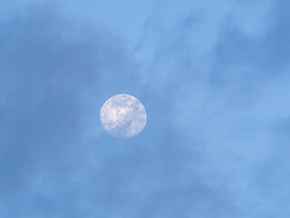 Full moon among clouds and blue sky