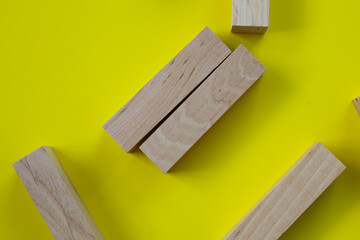 Wooden game blocks, chaotically scattered on a bright yellow background. This composition symbolizes creativity, strategic thinking, and endless possibilities for building.