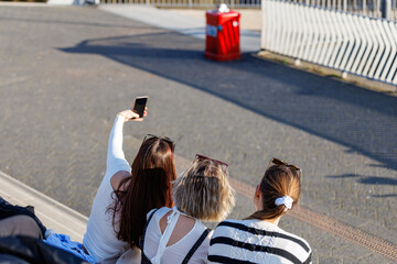 three ladies with sunglasses taking a selfie with a smartphone