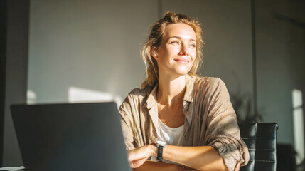 A smiling young woman sits at her home office desk with laptop, bathed in warm sunlight. This image captures essence of successful freelancer or remote worker enjoying her career and work-life balance