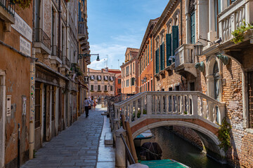 A photo of a narrow canal with a bridge and buildings