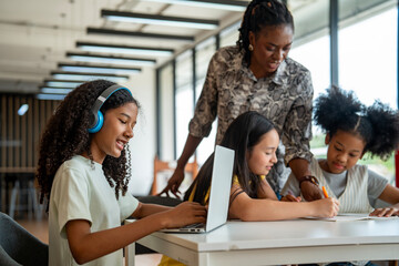 African school teacher is teaching and guiding group of young student in the class using...
