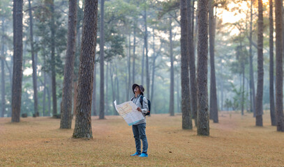 Asian naturalist looking at the map for direction while exploring wildlife in the pine forest for surveying and discovering the rare biological diversity and ecologist on the field study concept