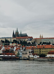 Obraz premium Beautiful view of Prague Castle and riverside buildings under a gray sky during early evening
