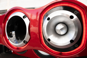 Automotive sound system with metal horn and aluminum flange, fixed to automotive acoustic panel with metallic red finish for high sound efficiency.