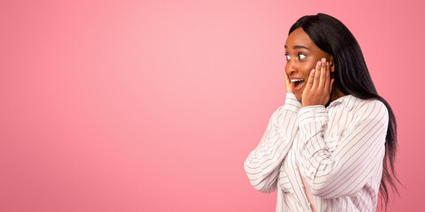 Excited African American woman looking at blank space on pink studio background, panorama....