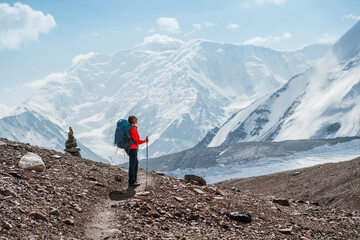 Lonely Climber woman with backpack and trekking poles during Lenin peak ascent enjoying mountain...