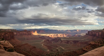 Naklejka premium Dramatic Canyonlands Vista: Towering Cliffs, Stormy Skies, and Golden Light