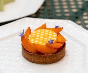 Close up of piece of apricot tartlet made with shortbread pastry, decorated honey jelly with mini...