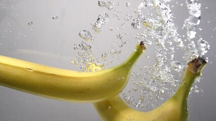 Two bananas plummet into pure, clear water, surrounded by splashing droplets - Powered by Adobe