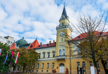 Kikinda City Hall stands as a historic landmark with a tall clocktower and red-tiled roofs. Its...