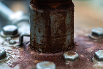 Close-up of an old metal pipe connection heavily corroded with rust, surrounded by bolts and industrial surface grime.