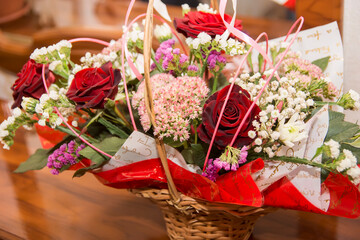 Beautiful floral arrangement of red roses and mixed flowers in a decorative basket for a special...