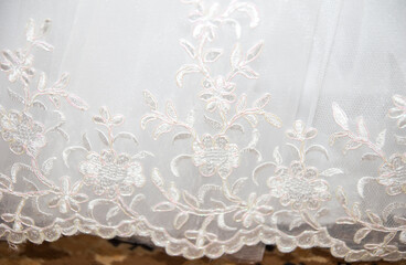 Delicate white fabric with intricate floral embroidery showcases elegance and craftsmanship in...
