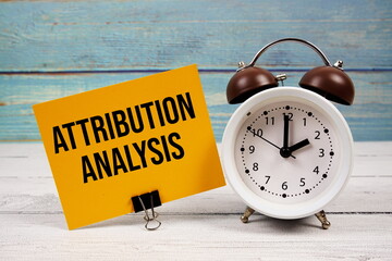 Attribution Analysis text written on paper card with alarm clock on wooden background