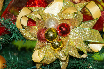 Brightly colored holiday bow decoration on a festive green Christmas tree adorned with ornaments...