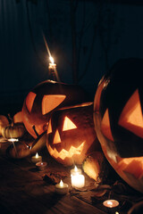 Happy Halloween. Jack o lantern glowing pumpkins with candles on rustic table in dark scary garden....