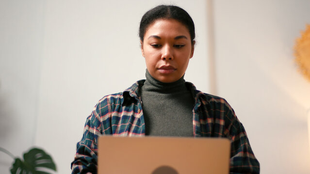 Hispanic woman type on laptop keyboard sitting on sofa