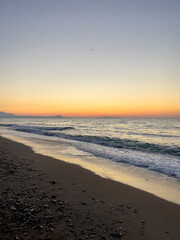 Sunrise colors stretch over the Cretan coastline. Concept of a calm, freedom, and the meditative stillness of early morning by the sea in Crete.