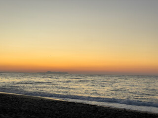 Soft waves meet the beach on Crete at sunrise. Concept of a peaceful beginning of a day by the Mediterranean on the island of timeless beauty.
