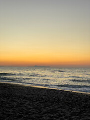 Morning sea greets the Cretan shore with golden light. Concept of a tranquil moment of solitude and connection with nature on the coast of Crete.