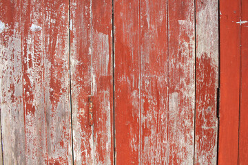 Naklejka premium Weathered Red Wooden Wall. A vintage red wooden wall with peeling paint and visible texture, ideal for rustic or antique themes.
