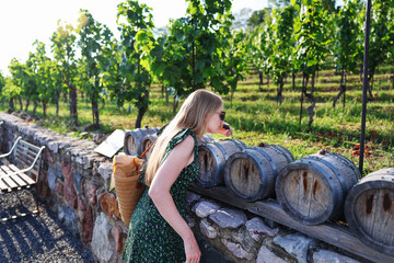 Female traveler enjoying vineyard tour, discovering small wine barrels, summer adventure.