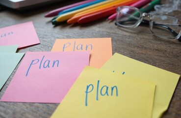 Desk workspace with organization supplies. White notebook with pink cover and blue pen. Sticky notes in orange stack next to gray ruler. Tools for planning and brainstorming.