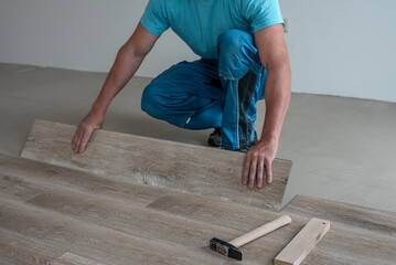 Floating floor work. The worker inserts the board of vinyl plank to the click system of Floating...