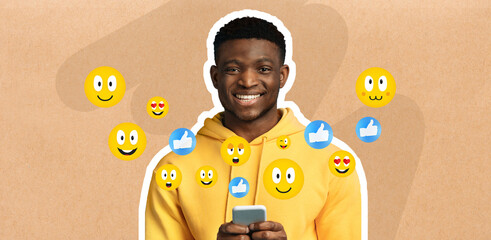 African American guy smiles while holding a smartphone, engaged in chatting and messaging on social...