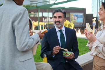 Multi ethnic business team enjoying a healthy lunch break together outdoors