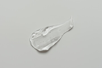 Smear of transparent cosmetic gel on gray background, skin care serum