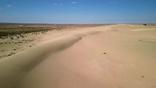 Aerial flyover of a desert landscape and a sand dune in the Aral Sea region of Kazakhstan.
