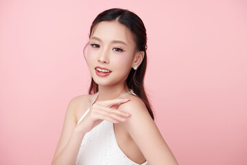 A beautiful young Asian woman with clean, fresh skin against a pink background. Skincare, facial treatment, cosmetology, beauty, and spa. An elegant portrait of an Asian woman.