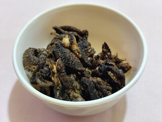 Flourless snail chips have a savory, delicious and crunchy taste. Presented with a white bowl with a natural blur background.