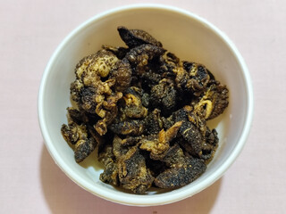 Flourless snail chips have a savory, delicious and crunchy taste. Presented with a white bowl with a natural blur background.