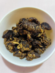 Flourless snail chips have a savory, delicious and crunchy taste. Presented with a white bowl with a natural blur background.