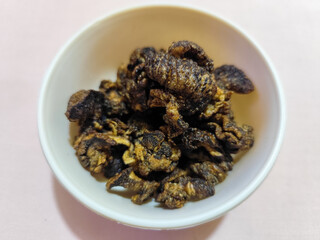 Flourless snail chips have a savory, delicious and crunchy taste. Presented with a white bowl with a natural blur background.