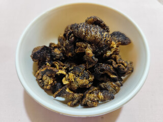 Flourless snail chips have a savory, delicious and crunchy taste. Presented with a white bowl with a natural blur background.